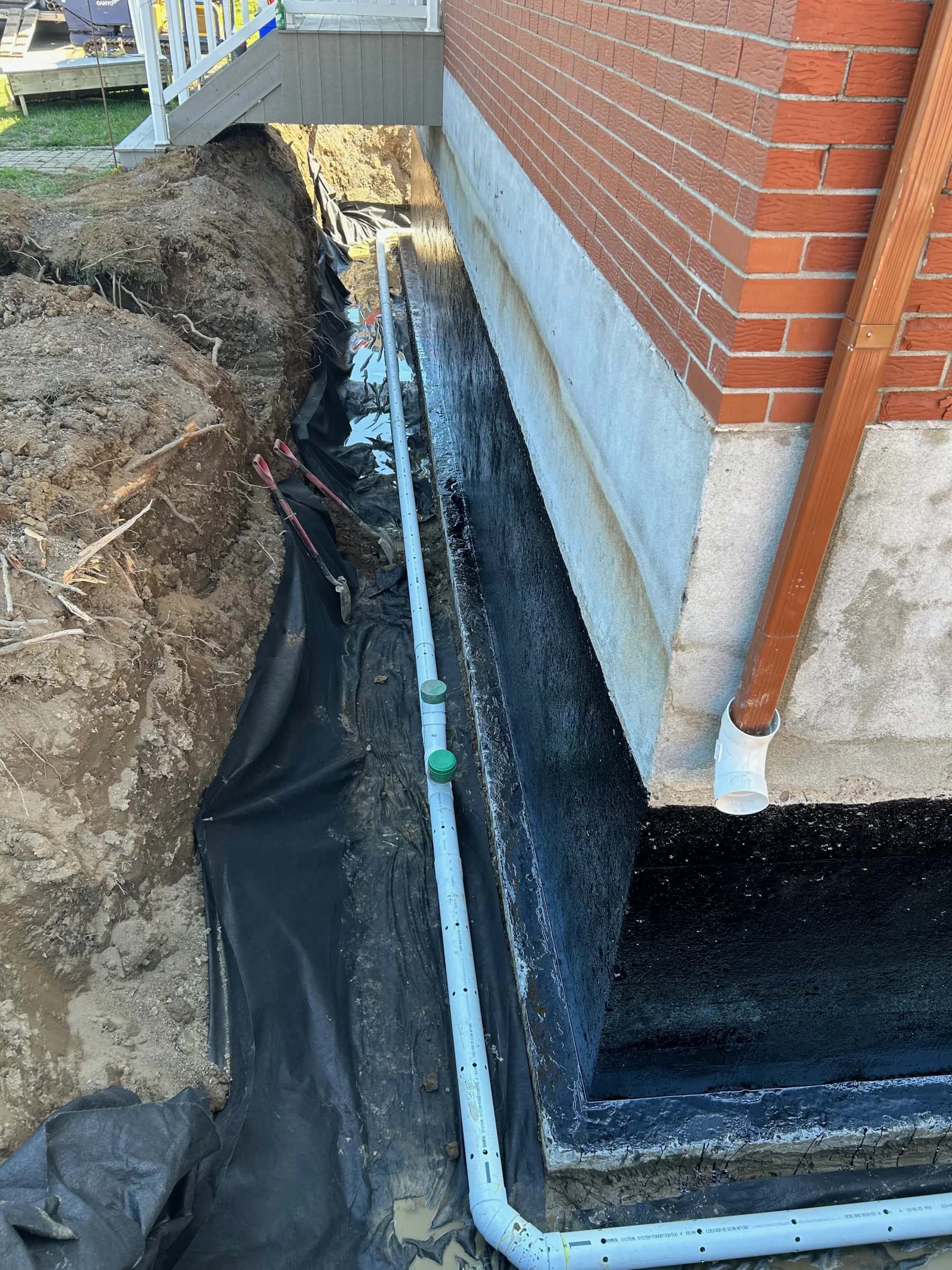 Drainage périphérique neuf posé le long d’une fondation en briques