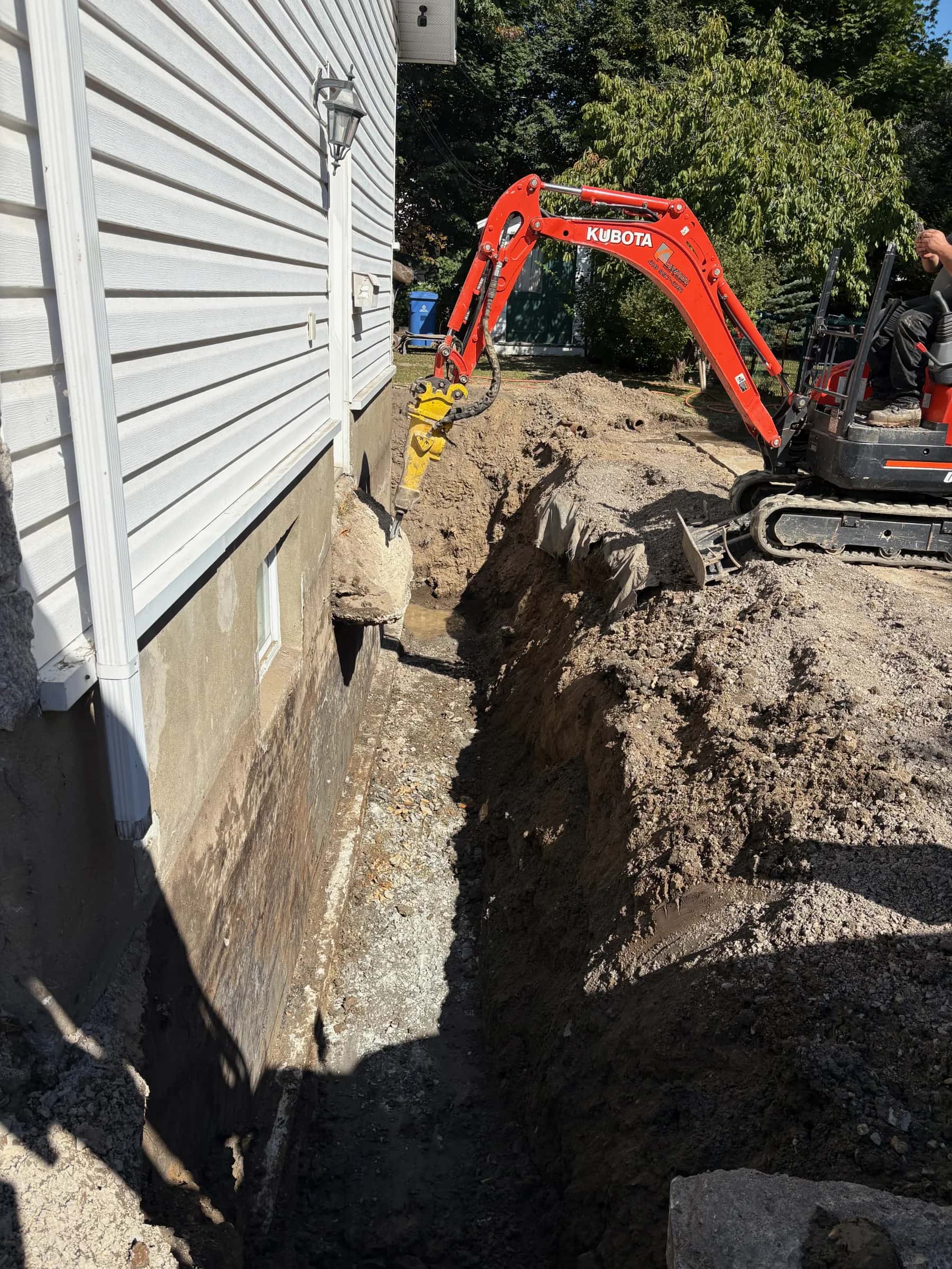 Tranchée creusée le long d’une fondation résidentielle avec une mini-excavatrice