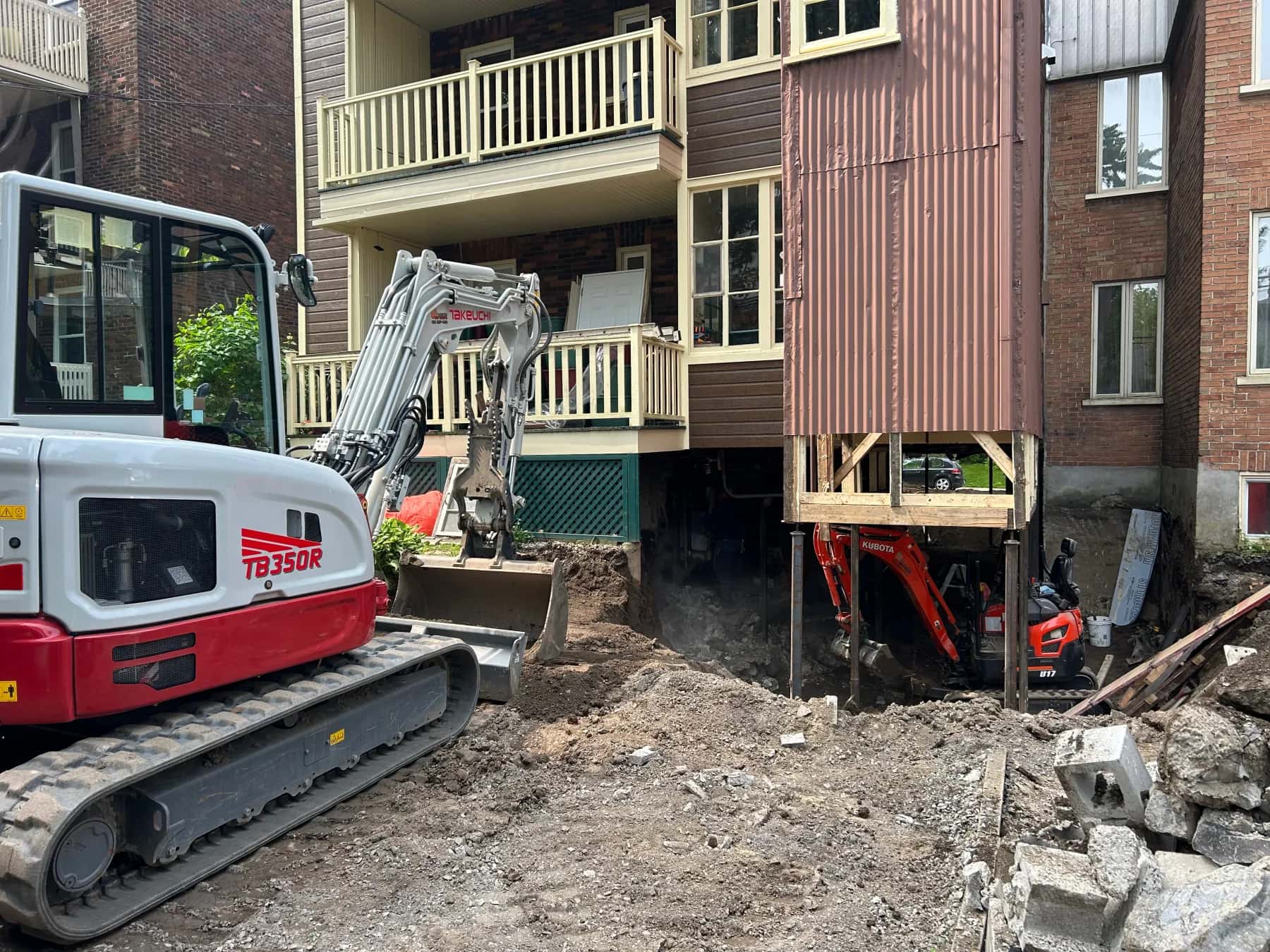 Excavatrice au travail sous un bâtiment résidentiel soutenu temporairement