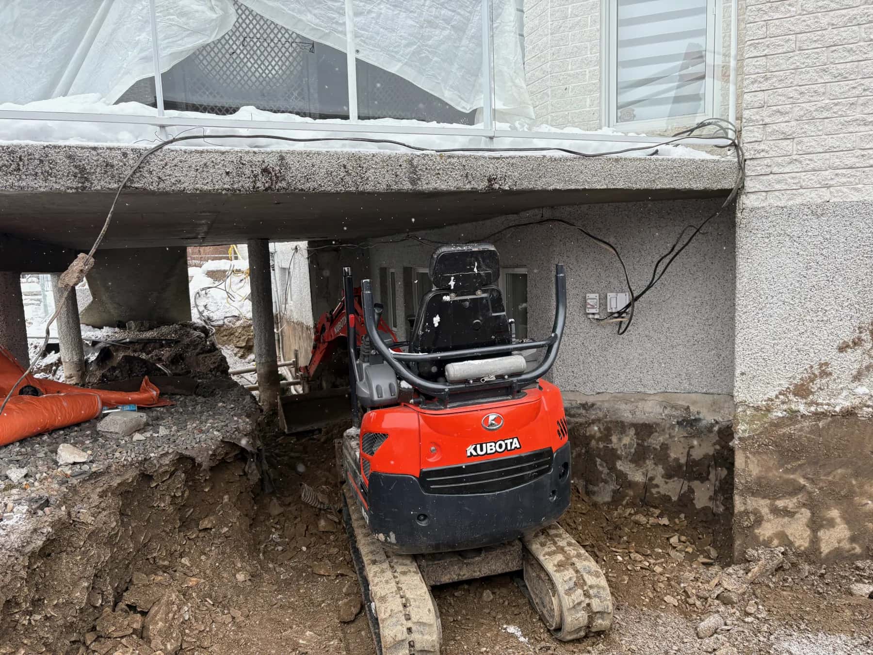 Mini-excavatrice opérant sous une maison dans un espace restreint
