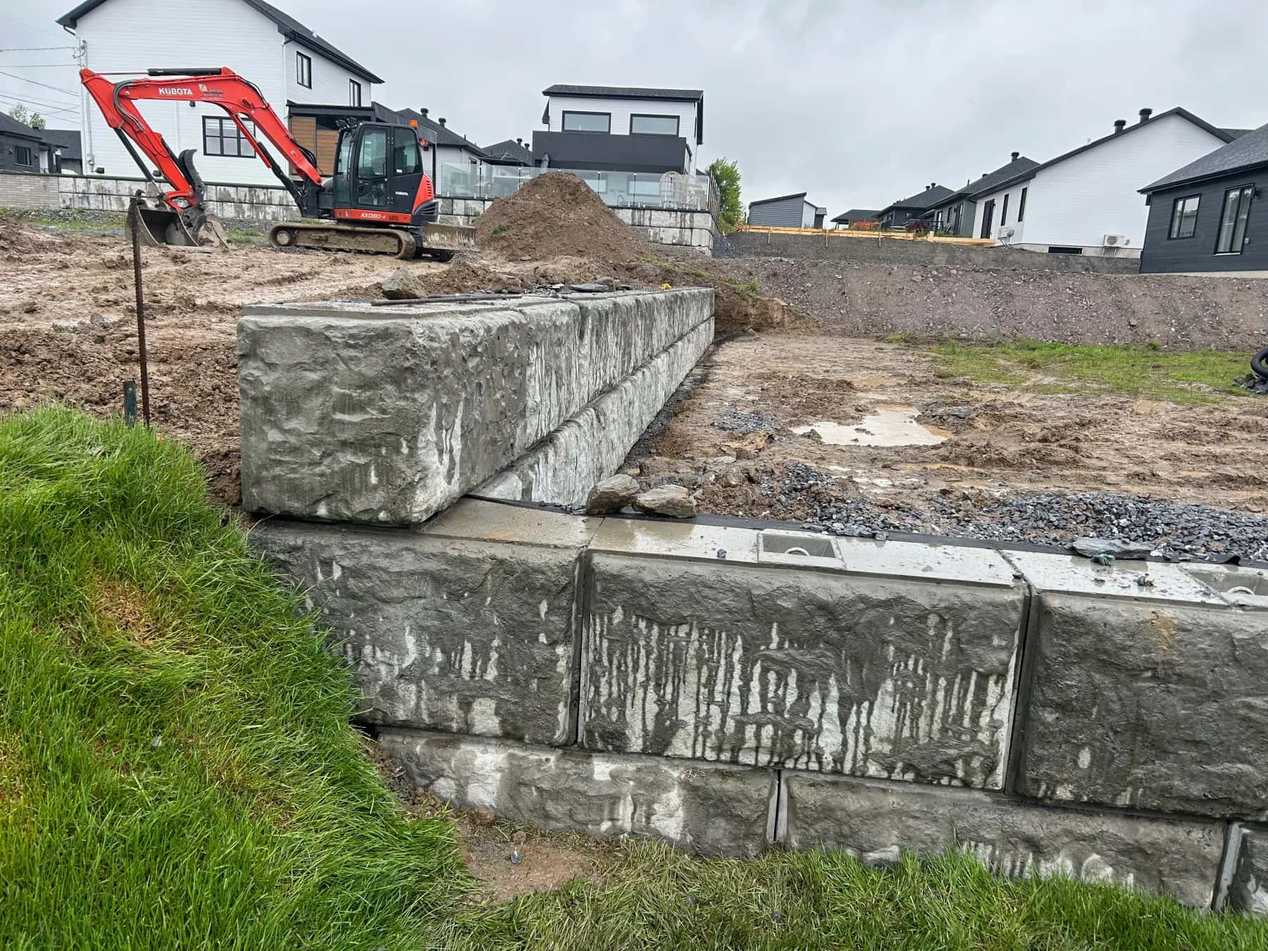 Chantier de mur de soutènement avec excavatrice et préparation du terrain